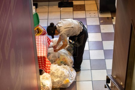 Foto de Tokio, Japón, 3 de noviembre de 2023: Trabajador organizando bolsas de basura en la cocina del restaurante - Imagen libre de derechos