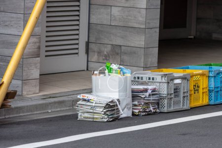 Photo for Tokyo, Japan, 3 November 2023: Recycle bins and newspapers stacked on sidewalk - Royalty Free Image