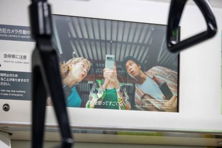 Téléchargez les photos : Tokyo, Japon, 3 Novembre 2023 : Publicité sur le train avec des personnes utilisant des smartphones - en image libre de droit