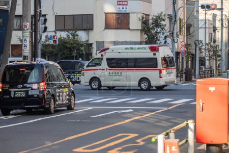 Téléchargez les photos : Tokyo, Japon, 3 novembre 2023 : Ambulance et taxi dans la rue avec panneaux de signalisation - en image libre de droit