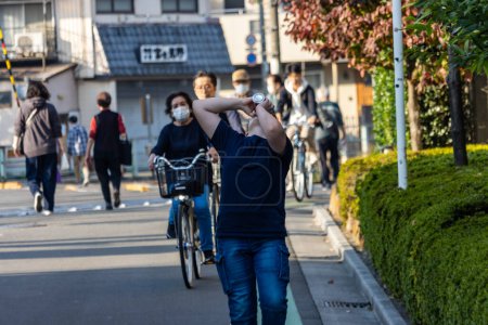 Foto de Tokio, Japón, 3 de noviembre de 2023: Hombre protegiendo los ojos del sol en la calle de la ciudad - Imagen libre de derechos