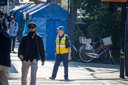 Téléchargez les photos : Tokyo, Japon, 4 novembre 2023 : Le personnel de sécurité en service au milieu des activités quotidiennes de la rue - en image libre de droit