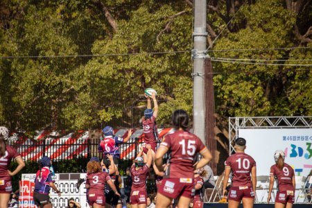 Photo for Tokyo, Japan, 4 November 2023: Dynamic Women's Rugby Match with Team in Maroon Jerseys - Royalty Free Image