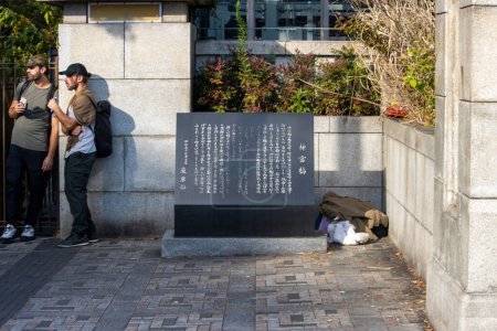 Téléchargez les photos : Tokyo, Japon, 4 novembre 2023 : Conversation décontractée à côté d'une plaque d'information dans un parc de Tokyo - en image libre de droit