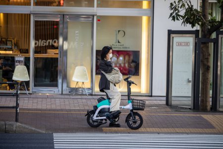 Téléchargez les photos : Tokyo, Japon, 4 novembre 2023 : Une femme sur un vélo électrique moderne en attente aux feux de circulation dans la ville - en image libre de droit