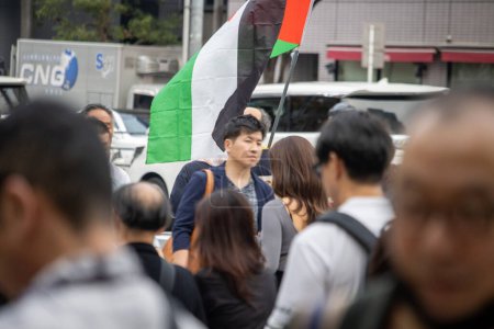 Foto de Tokio, Japón, 4 de noviembre de 2023: Bandera palestina ondeada en una calle concurrida de Tokio - Imagen libre de derechos