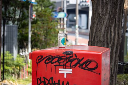 Photo for Tokyo, Japan, 4 November 2023: Discarded Beverage Can on Graffiti-Covered Japan Post Mailbox - Royalty Free Image