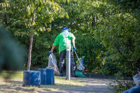 Téléchargez les photos : Tokyo, Japon, 4 novembre 2023 : Un travailleur municipal en uniforme vert vif ramasse des ordures dans un parc municipal - en image libre de droit