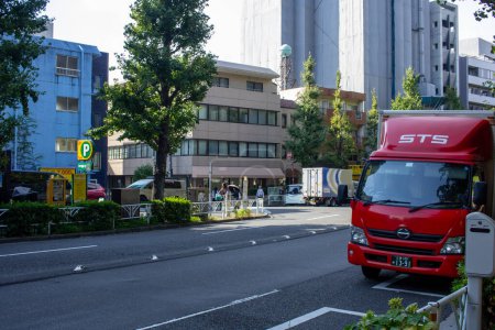 Photo for Tokyo, Japan, 4 November 2023: Red STS Delivery Truck Parked on a Busy Tokyo Street - Royalty Free Image