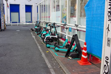 Téléchargez les photos : Tokyo, Japon, 4 Novembre 2023 : Station de location de scooter électrique organisée sur la rue Tokyo avec des cônes de sécurité et des barrières - en image libre de droit
