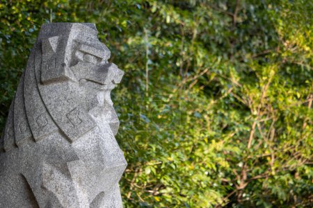Foto de Tokio, Japón, 4 de noviembre de 2023: Estatua de león de piedra en la vegetación - Imagen libre de derechos