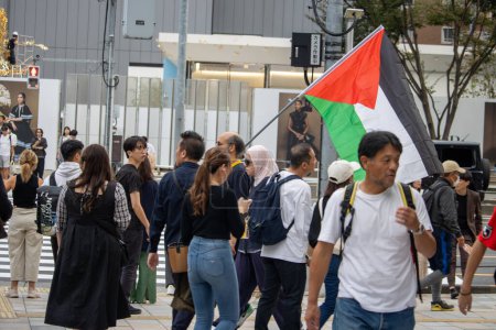 Foto de Tokio, Japón, 4 de noviembre de 2023: Multitud diversa en un evento al aire libre con bandera palestina - Imagen libre de derechos