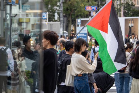 Foto de Tokio, Japón, 4 de noviembre de 2023: Manifestantes con bandera palestina en el entorno urbano - Imagen libre de derechos