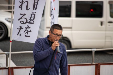 Téléchargez les photos : Tokyo, Japon, 5 novembre 2023 : Un homme parle dans un micro à côté de bannières de protestation - en image libre de droit