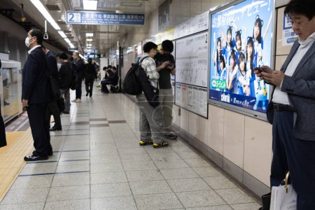 Téléchargez les photos : Tokyo, Japon, 6 novembre 2024 : Voyageurs à la gare avec publicité en arrière-plan - en image libre de droit