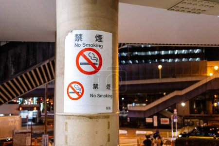 Foto de Tokio, Japón, 7 de noviembre de 2024: No hay señales de fumar en un poste por la noche - Imagen libre de derechos