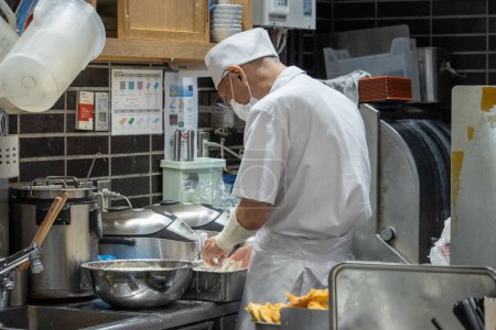 Photo for Tokyo, Japan, 7 November 2024: Chef Preparing Food in a Busy Kitchen - Royalty Free Image