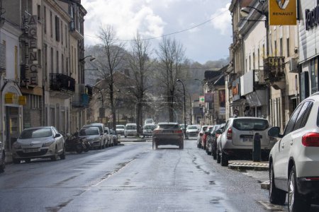 Téléchargez les photos : France, 1 avril 2024 : Rue urbaine humide avec voitures stationnées et concessionnaire Renault - en image libre de droit