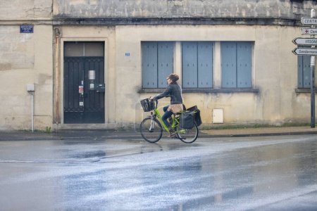 Foto de Francia, 01 de abril de 2024: Ciclista paseando por una calle lluviosa en una ciudad francesa - Imagen libre de derechos