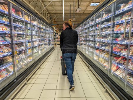 Téléchargez les photos : France, 23 mars 2024 : Une femme fait ses courses dans un rayon surgelé d'un supermarché - en image libre de droit