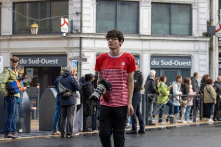 Téléchargez les photos : France, 22 mai 2024 : Photographe de rue en chemise rouge devant la Gare du Sud-Ouest. - en image libre de droit