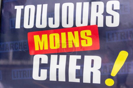 Téléchargez les photos : France, 22 Mai, 2024 : Affichage promotionnel indiquant "Toujours Moins Cher !" sur une fenêtre de magasin. - en image libre de droit