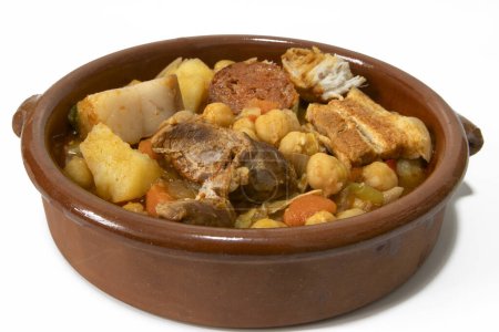 Foto de Un tazón de barro con un guiso de garbanzo andaluz, aislado sobre un fondo blanco, de cerca. Concepto de comida española. - Imagen libre de derechos
