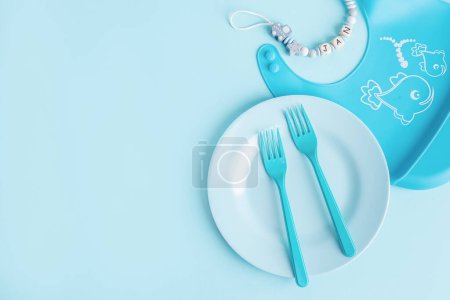 Téléchargez les photos : Blue plate with blue cutlery on blue background. Baby food concept. - en image libre de droit