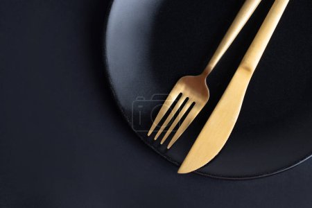 Photo for Golden cutlery on plate on dark background. Closeup. Eating concept. - Royalty Free Image