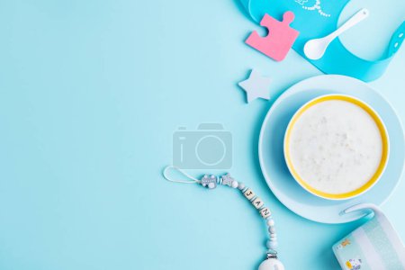 Téléchargez les photos : Baby porridge with cutlery on blue background. Baby food concept. - en image libre de droit
