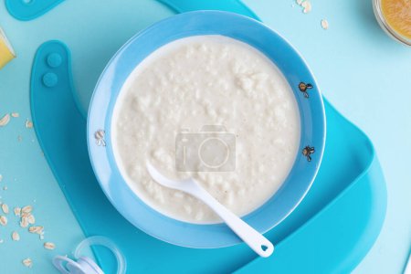 Téléchargez les photos : Baby porridge with cutlery on blue background. Baby food concept. - en image libre de droit