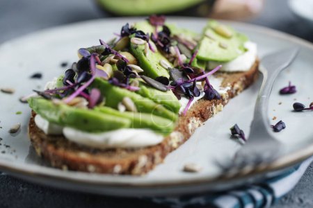 Foto de Toast with avocado on plate on grey background. Closeup - Imagen libre de derechos