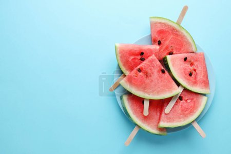 Foto de Watermelon cuts pieces on blue plate on bright background. Top View. Summer concept. - Imagen libre de derechos