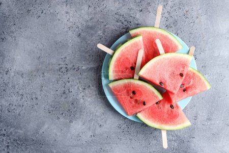 Foto de Watermelon cuts pieces on blue plate on bright background. Top View. Summer concept. - Imagen libre de derechos