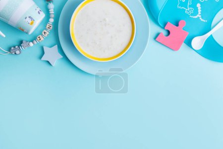 Foto de Baby porridge with cutlery on blue background. Baby food concept. - Imagen libre de derechos