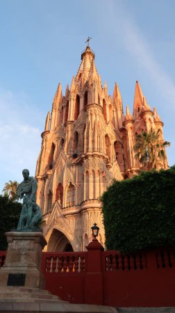 Foto de La hermosa iglesia / catedral Parroquia de San Miguel Arcangel con la estatua de Fray Juan de San Miguel en frente, San Miguel de Allende, México 2022 - Imagen libre de derechos