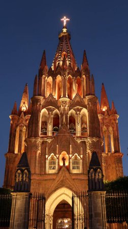 Foto de La fascinante fachada frontal de la iglesia / catedral Parroquia de San Miguel Arcangel en San Miguel de Allende por la noche, México 2022 - Imagen libre de derechos