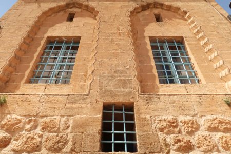 Three windows on the facade of a traditional house in the old town of Mardin, decorated with elaborate carved patterns and details, Mardin, Turkey 2022