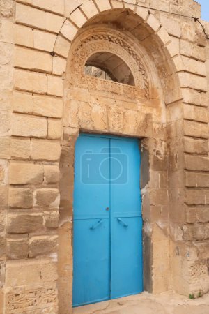 Bright blue door in an elaborate facade of a traditional house in the old town of Mardin, Turkey 2022