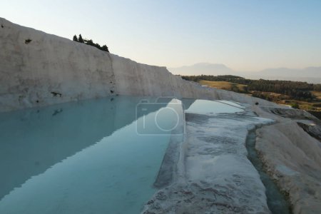 Intense blue water in the travertine terraces at Pamukkale in the early morning, Denizli, Turkey 2022
