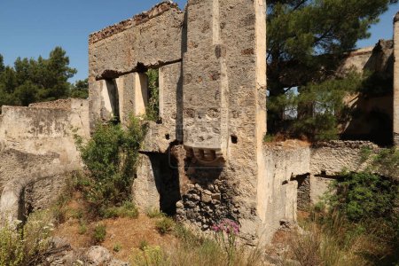 Reste der Außenwand eines Hauses im verlassenen Dorf Kayakoy mit Schornstein, Fenstern und Garten, in der Nähe von Fethiye, Türkei