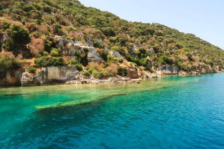 Submerged wall next to remaining structures onshore at the ancient sunken city of Kekova, Kekova Island, Demre, Turkey 2022