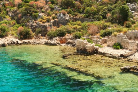 Submerged foundation next to remaining walls and structures onshore at the ancient sunken city of Kekova, Kekova Island, Demre, Turkey 2022