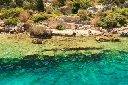 Submerged foundation in the foreground and structures onshore in the background at the ancient sunken city of Kekova, Kekova Island, Demre, Turkey 2022