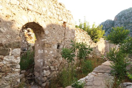 Eine Mauer mit einer Tür in den Ruinen der Kirche A an der antiken Stätte von Olympos, Olympos, Pflanzen, Büsche und Bäume überwuchern das Gebiet in der Nähe von Antalya, Türkei 2022