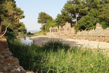 Foto de El río Goksu que fluye en la bahía de Cirali Koyu con las ruinas de una casa de baños junto a ella en el sitio antiguo de Olympos, Olympus, Turquía - Imagen libre de derechos