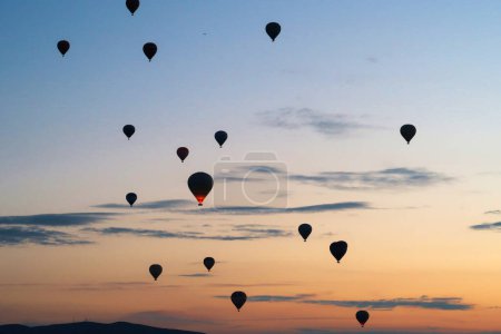Hot air balloons rising over the landscape of the Red Valley, Rose Valley before sunrise, close to Goreme, Cavusin, Cappadocia, Turkey 2022