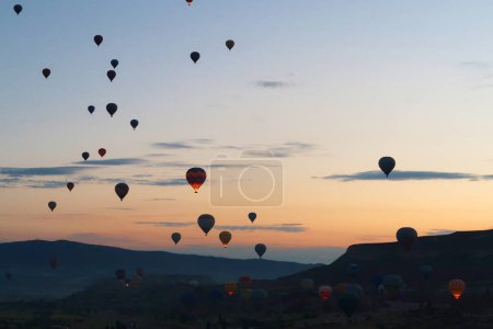 Many hot air balloons rising over the landscape of the Red Valley, Rose Valley before sunrise, close to Goreme, Cavusin, Cappadocia, Turkey 2022