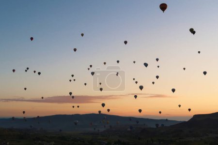 Dozens of hot air balloons rising over the landscape of the Red Valley, Rose Valley before sunrise, close to Goreme, Cavusin, Cappadocia, Turkey 2022
