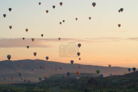 Dozens of colorful hot air balloons over the landscape of the Red Valley, Rose Valley right before sunrise, close to Goreme, Cavusin, Cappadocia, Turkey 2022